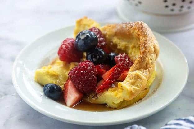 dutch baby pancake on white plate with fresh fruit