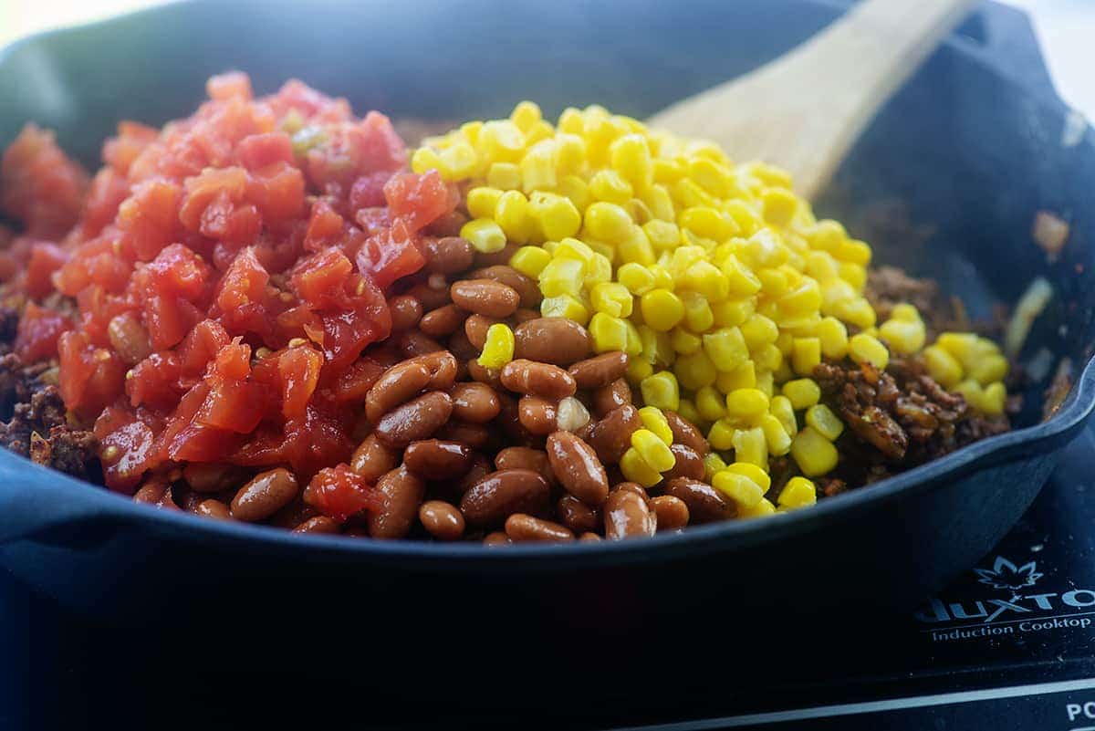 skillet full of beef, beans, corn, and tomatoes.