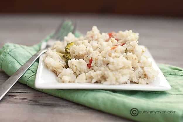 A close up of chicken and rice on a square plate on a folded cloth napkin.