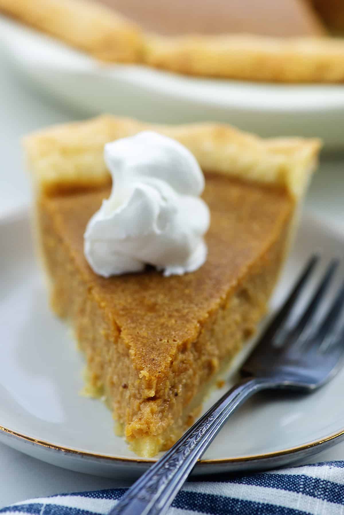 slice of pie on white plate with whipped cream on top.