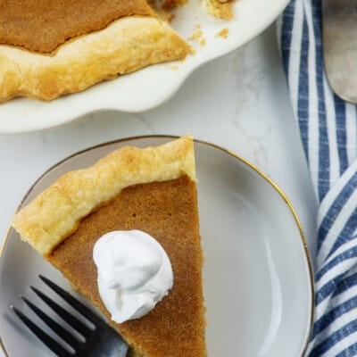 sweet potato pie on white plate with whipped cream.