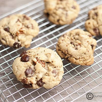 Five brown butter chocolate chip cookies on a wire cooling rack.