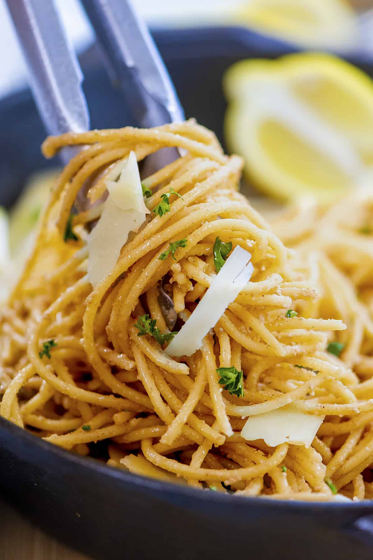 Lemon garlic pasta twirled on tongs.