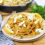 Plateful of spaghetti topped with parmesan and lemon.