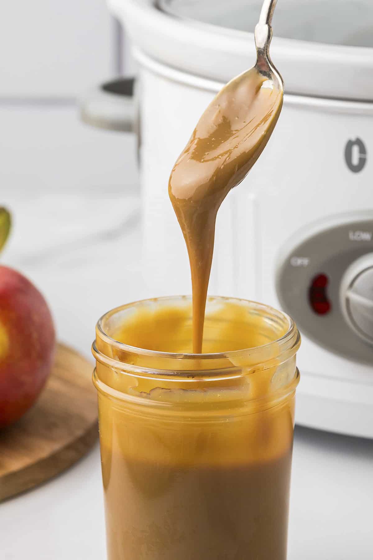 Dulce de leche on spoon over jar.