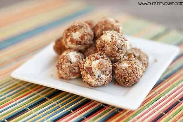 Several goat cheese balls with bacon on a colorful mat and white plate.