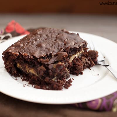 A close up of a gooey chocolate cake on a whtie plate