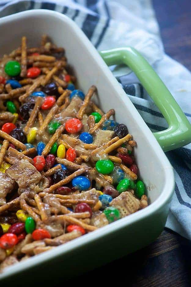 A baking pan with m&m\'s, pretzel sticks, and cereal.