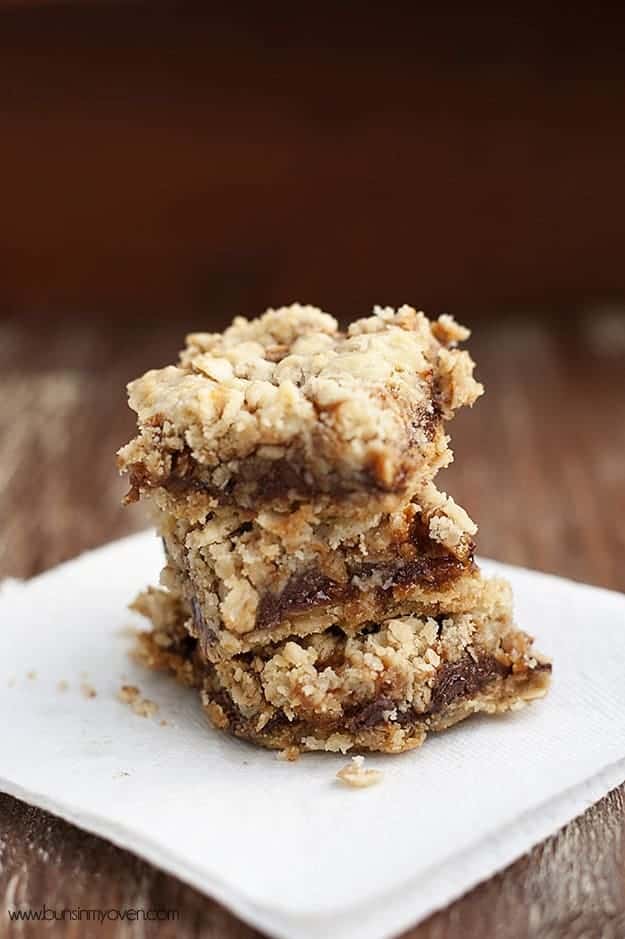 stacked oatmeal carmelitas on a wooden table.