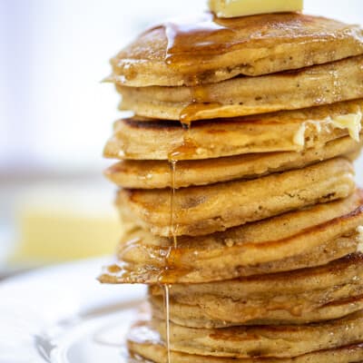 huge stack of fluffy buttermilk pancakes with syrup.
