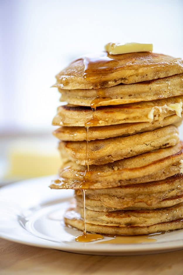 huge stack of fluffy buttermilk pancakes with syrup.