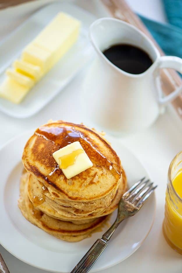 platter with pancakes, orange juice, butter, and syrup.