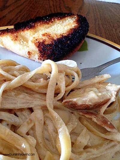 A closeup of chicken Alfredo and garlic bread on a plate 