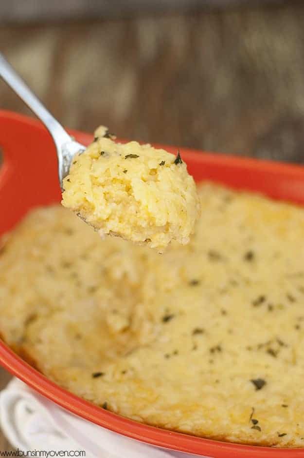 A spoonful of cheese grits above a pan of cheese grits 