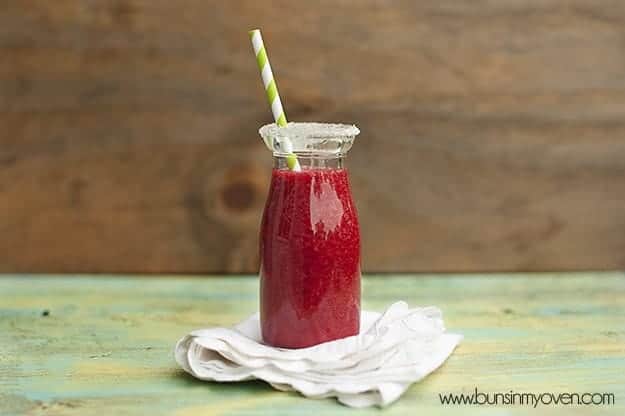 The milk jar of raspberry lemonade on a folded cloth napkin 