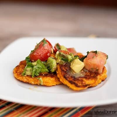 A closeup of corn cakes topped with avocado and tomato