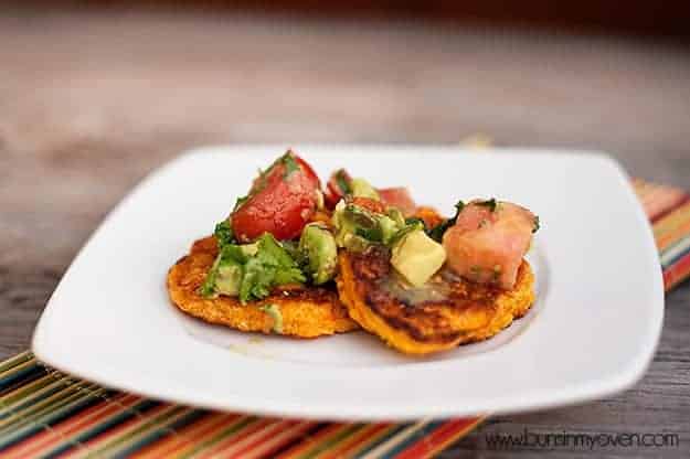 Corn cakes topped with avocado tomato relish on a white plate 