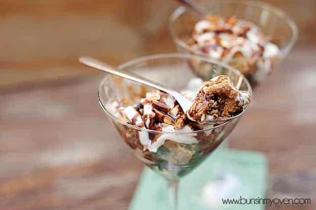 A close up of a pretzel brownie trifle in a martini glass with a spoon in it.