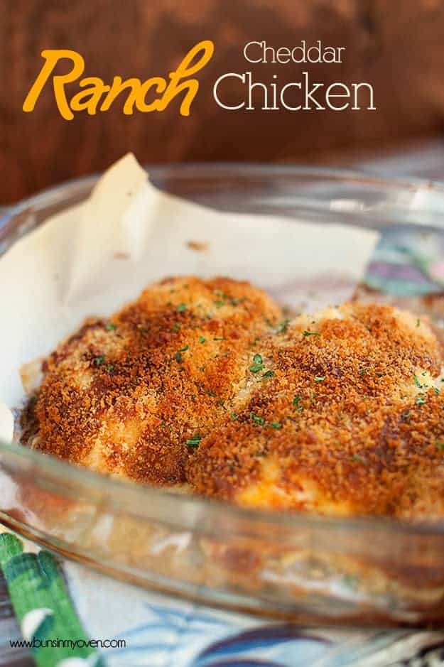 A close up of cheesy crusted chicken breast in a glass baking dish