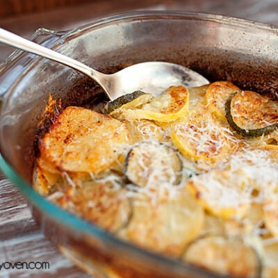 A clear glass baking dish with zucchini and shredded cheese in it.