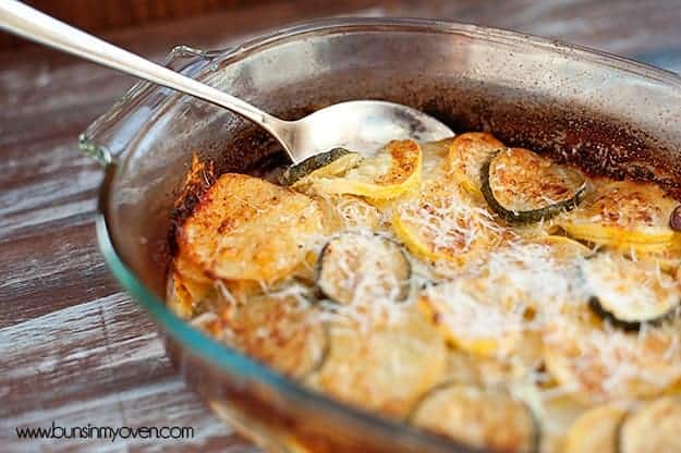 A clear glass baking dish with zucchini and shredded cheese in it.