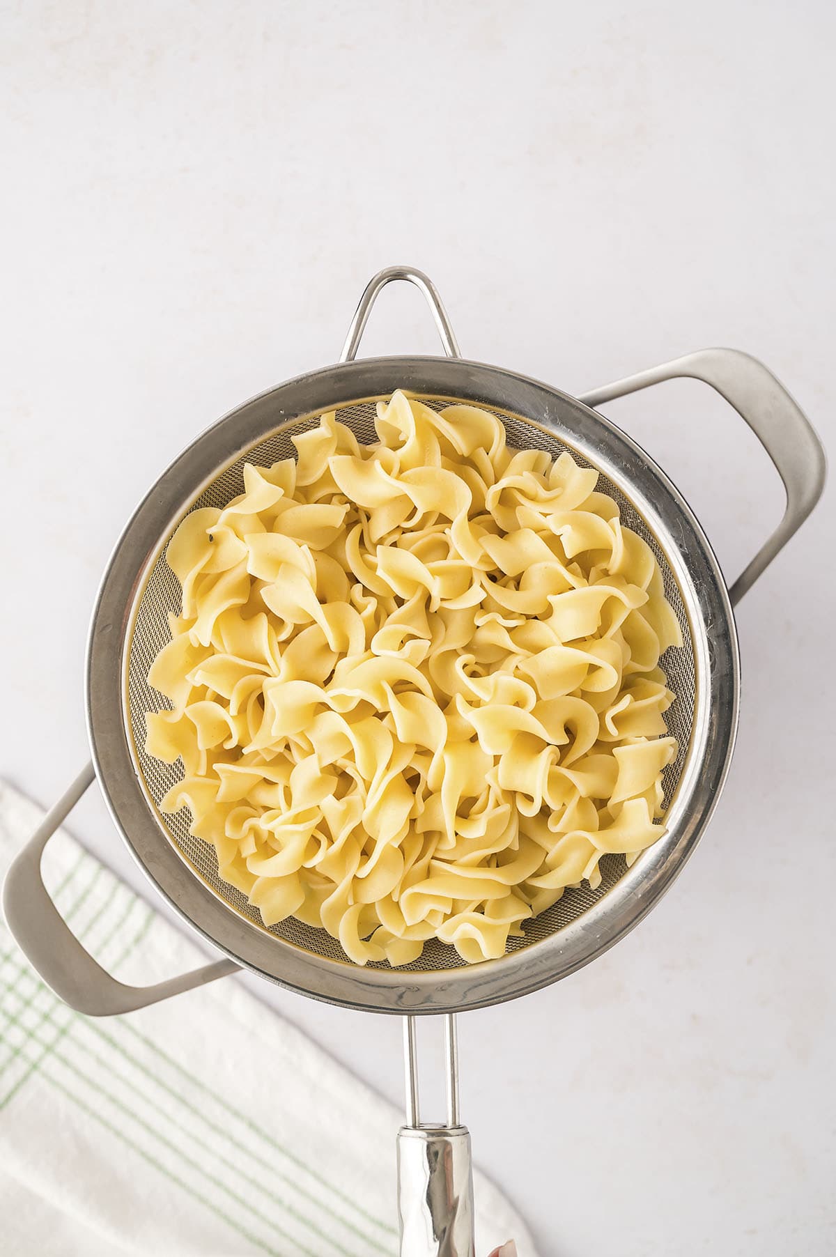 Cooked egg noodles in colander.