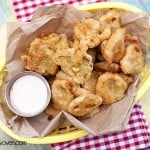 An appetizer basket with fried pickles and ranch dressing in it.