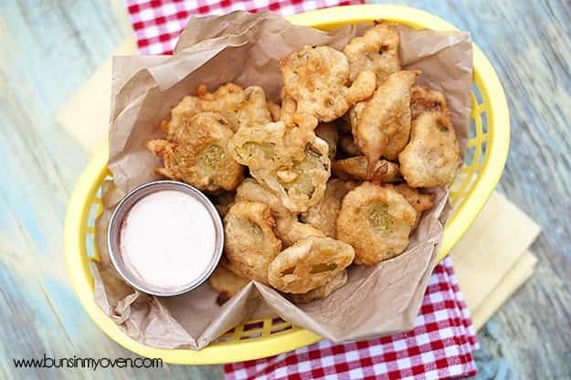 A basket full of fried pickles on top of a checkered cloth napkin