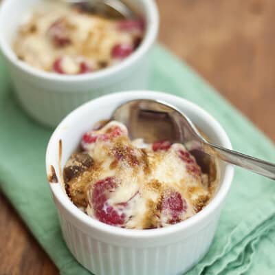 A white cup of raspberry gratin with a spoon in it.