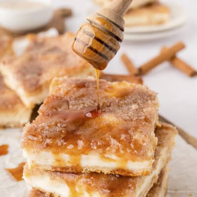 Honey being drizzled over sopapilla cheesecake bars.