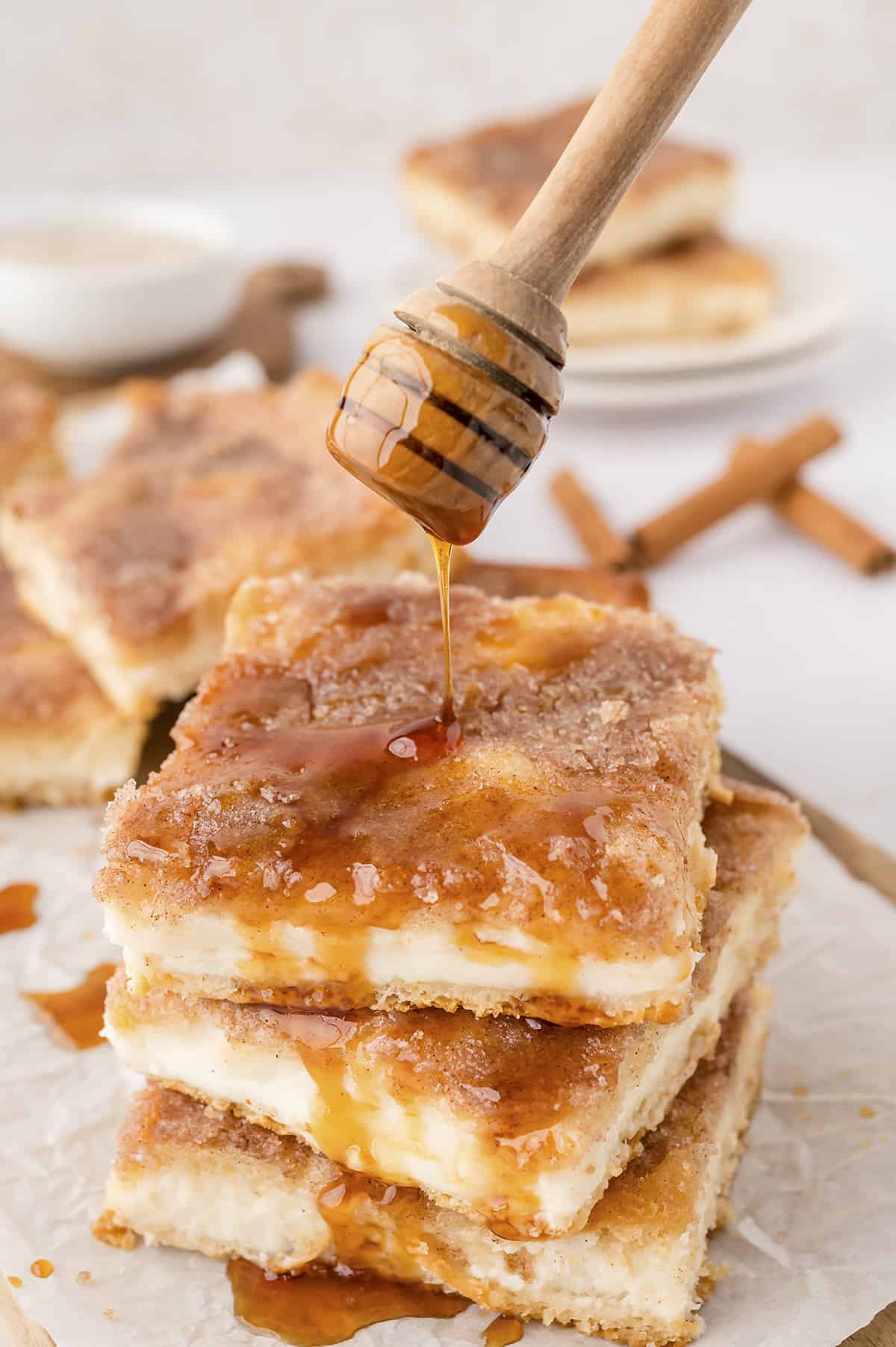 Honey being drizzled over sopapilla cheesecake bars.