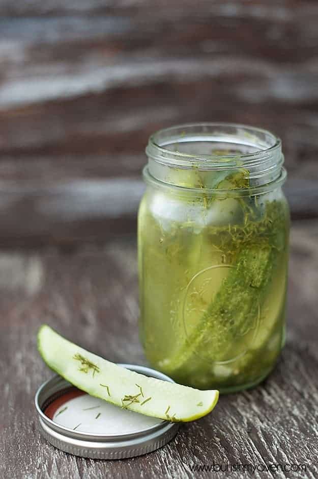 A glass jar full of sliced pickle spears.