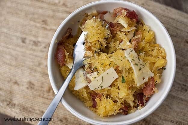 A spaghetti squash and a fork in a white bowl on a table.