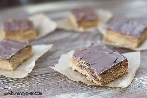 Peanut butter bars topped with chocolate frosting on wax paper.
