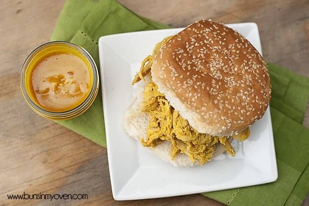 Overhead view of a jar of barbecue sauce next to a chicken sandwich.