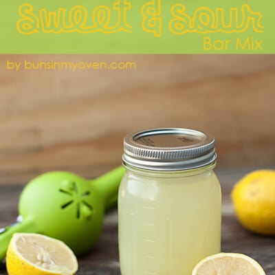 Sweet and sour mix in a jar next to a bunch of lemon slices.