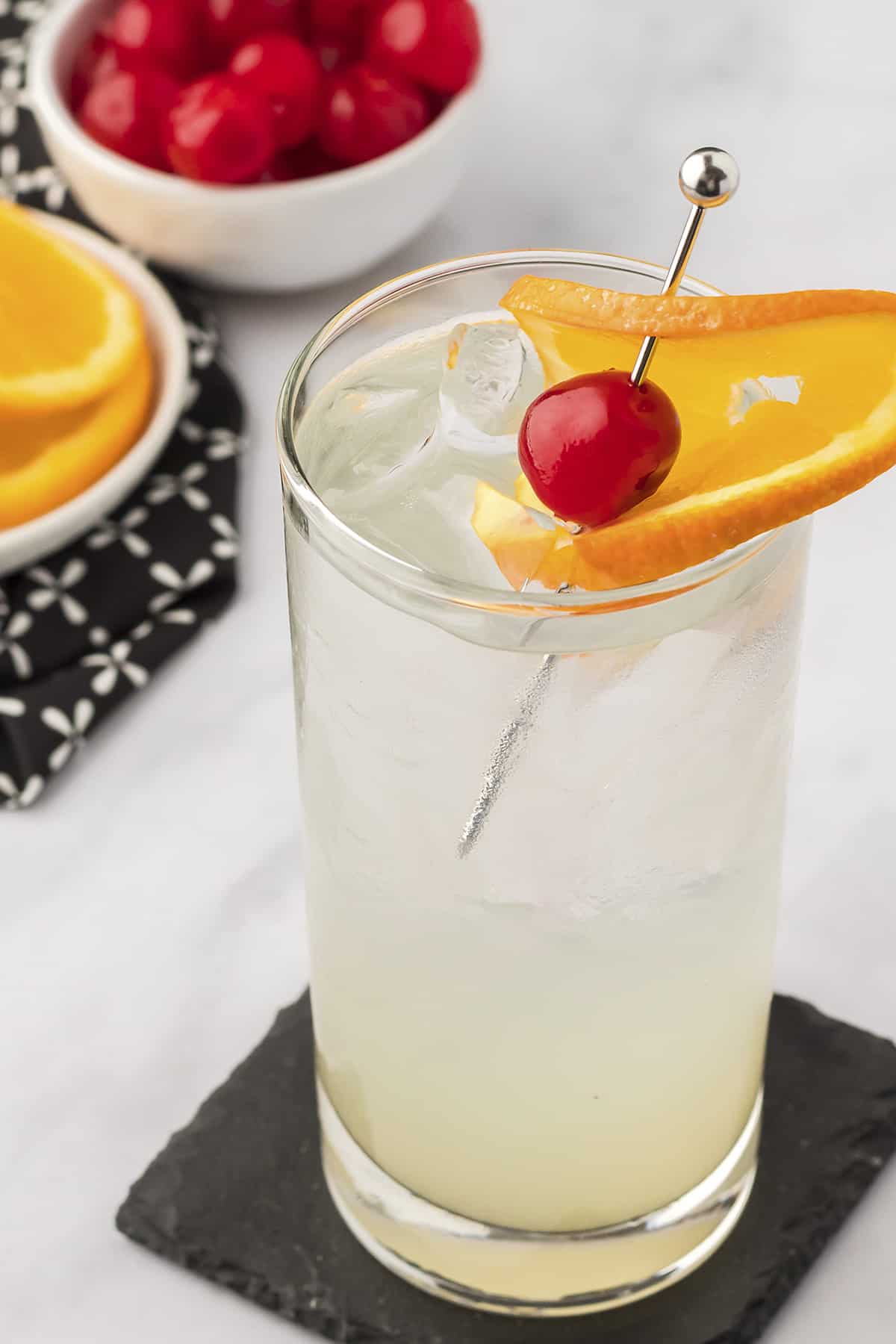 Vodka collins in glass with orange garnish.