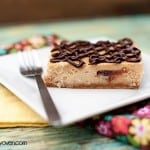 A peanut butter cheesecake bar on a square white plate.