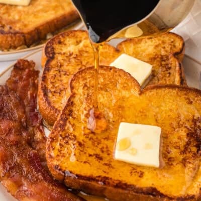 Syrup being poured over eggnog french toast recipe onm plate.