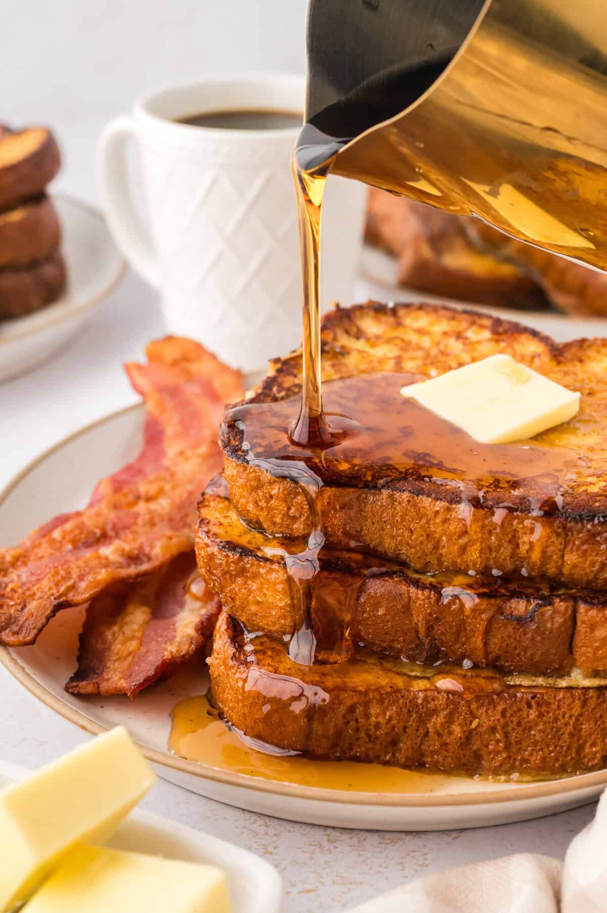 Maple syrup being drizzled over eggnog french roast recipe.