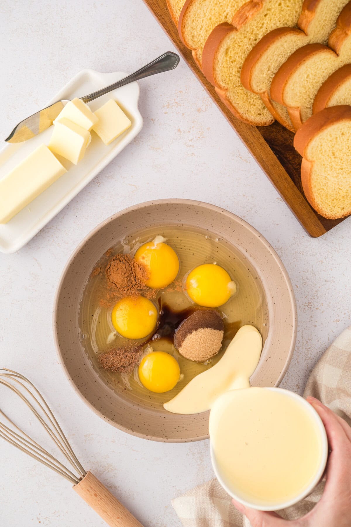 Eggnog being poured into dish with eggs to make eggnog french toast.