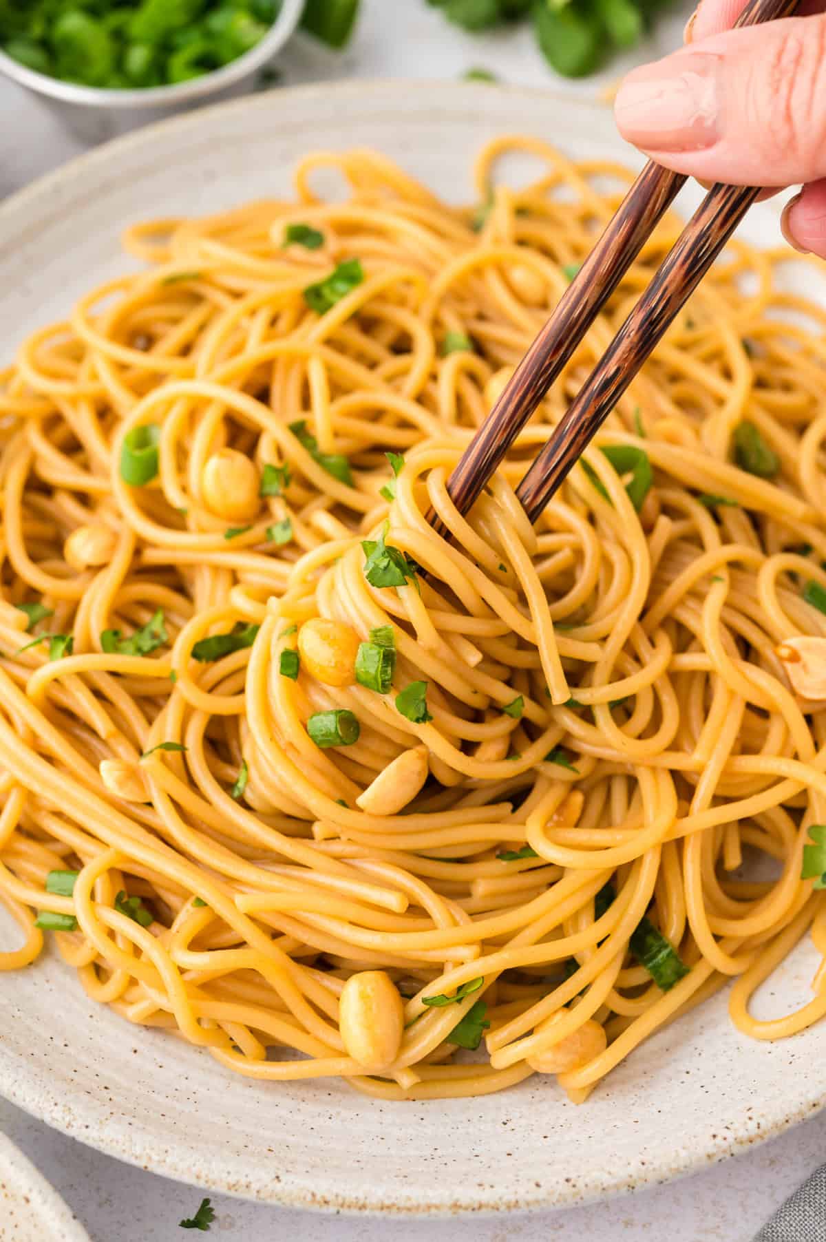 spicy Thai peanut noodles in white bowl with fork.