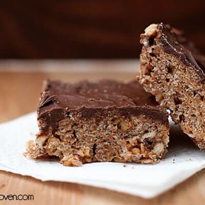 Two rice krispie squares with chocolate frosting on a folded paper towel.