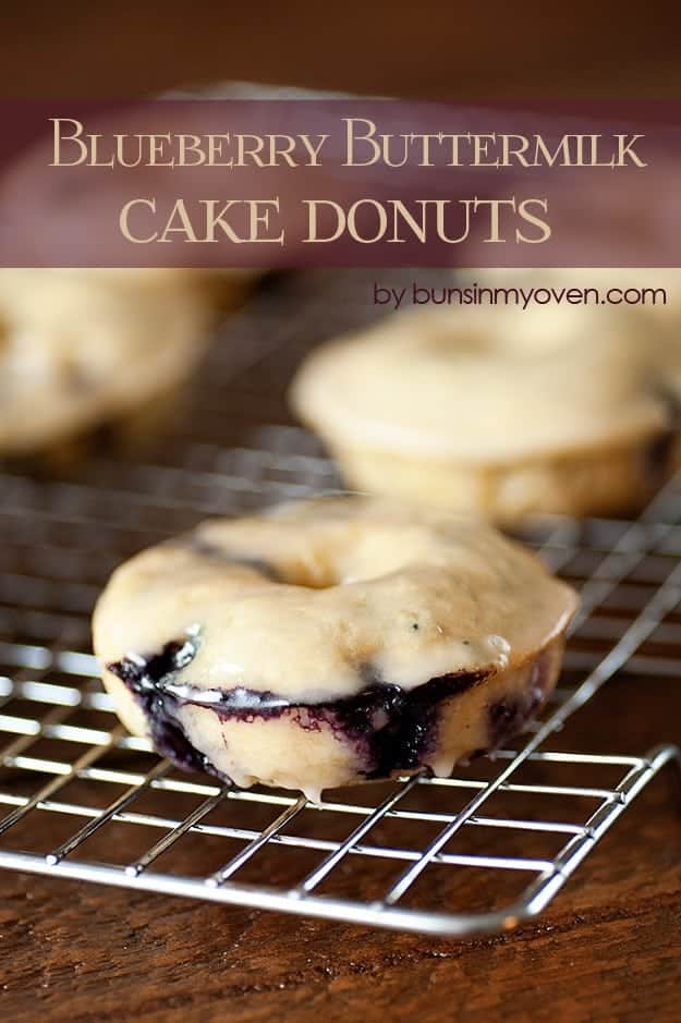 A few blueberry donuts on a wire cooling rack.