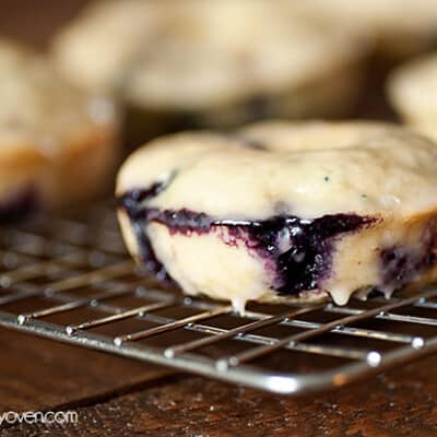 A close up of a blueberry donut on a cooling rack