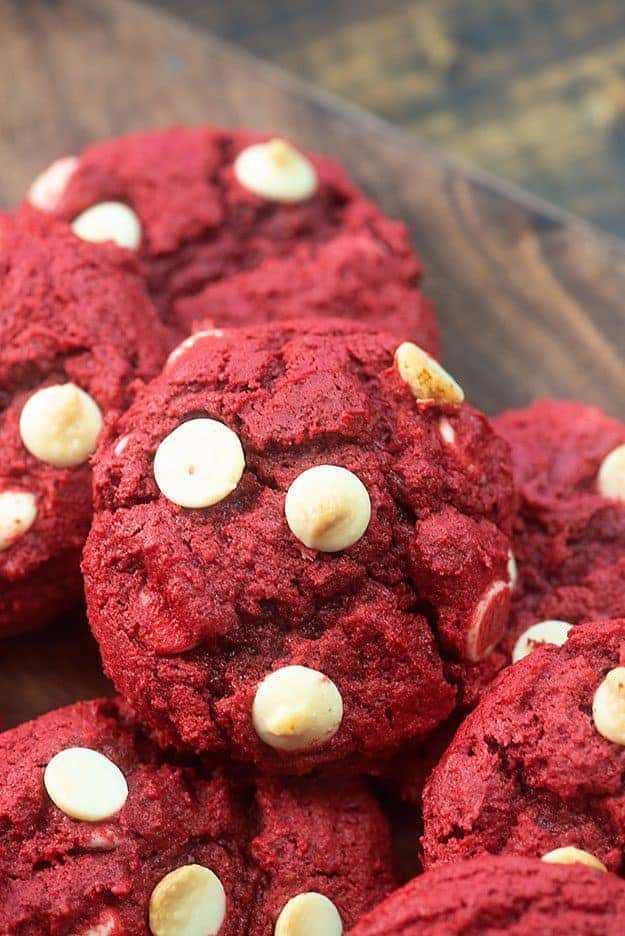 A pile of red velvet cookies on a wooden table.