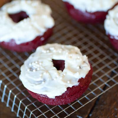 A close up of a white icing donut on a wire grid cooling rack.