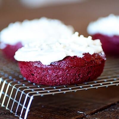 A few red velvet cake donuts on a cooling rack.