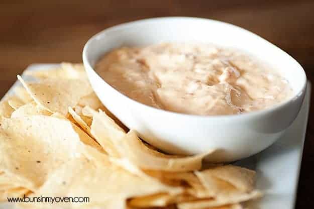 A close up of chips next to a white bowl of queso dip.