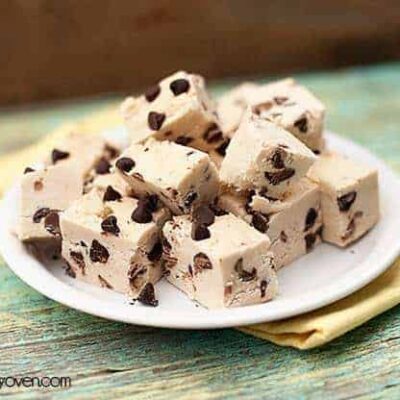 A pile of chocolate chip fudge on a small white plate.